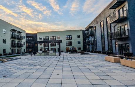 a courtyard with a sunset on grey and tan apartments with bolt-on balconies.