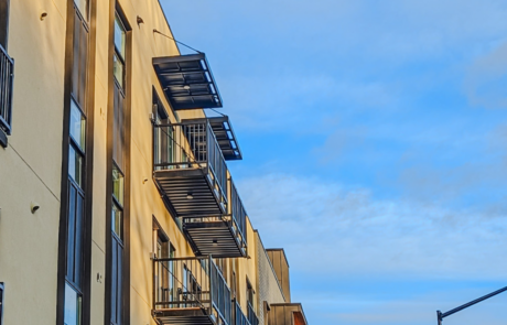 a sunset shot with aluminum canopies and bolt on balconies attached to a multifamily apartment