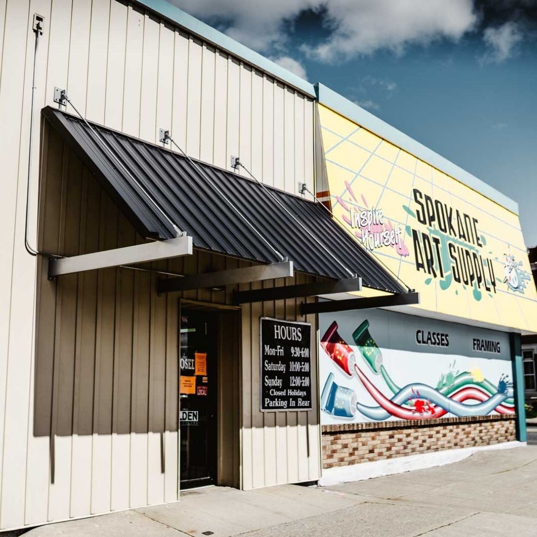 cream metal building with colorful wall art and a metal awning
