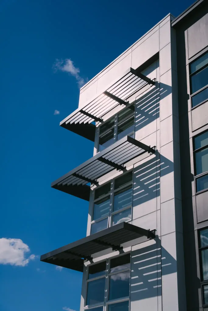 Millennium Monroe Aluminum Sunshades The image shows Vestis Architectural Products installed on Millennium Monroe, with aluminum louvered sunshade Architectural Systems casting angled shadows across the building’s windows.