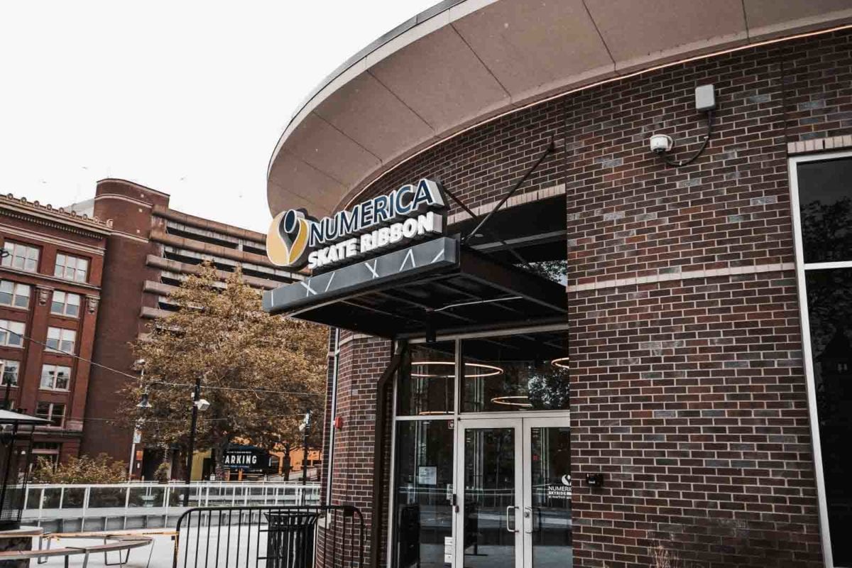 The image shows a public recreation building entrance with a Vestis black architectural canopy extending over the Numerica Skate Ribbon signage and walkway.
