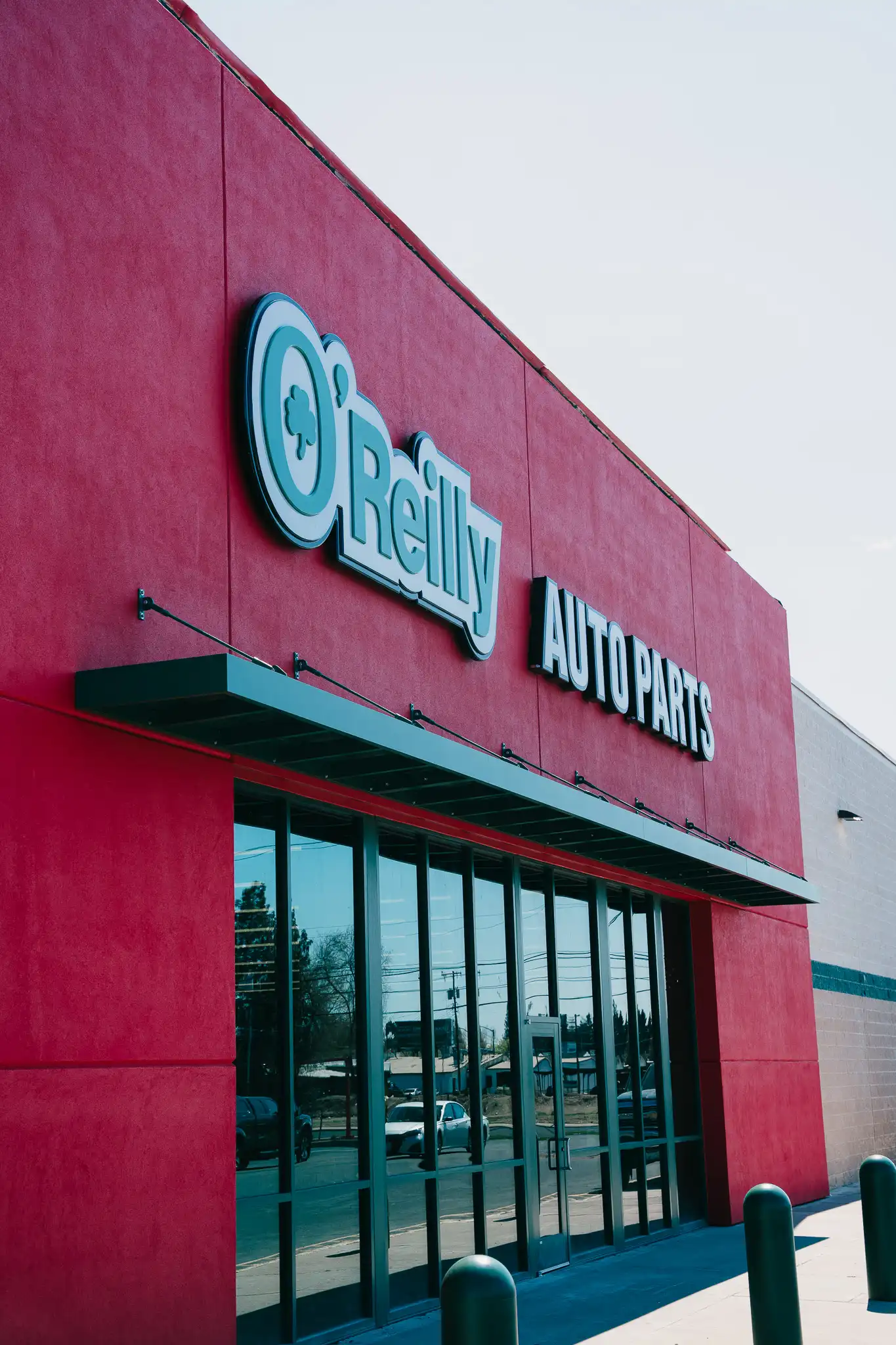 O’Reilly Auto Parts Entry Aluminum Canopy The image shows a Vestis aluminum canopy mounted above the glass entrance of an O’Reilly Auto Parts storefront with red exterior walls.