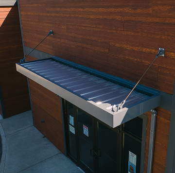 Vestis Aluminum Canopies & Awnings The image shows a Vestis aluminum canopy installed above a building entrance, providing weather protection with a clean metal profile.