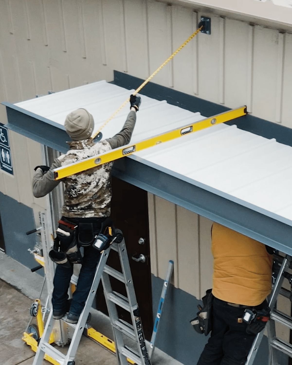 Vestis employees working on the exterior of a building canopy